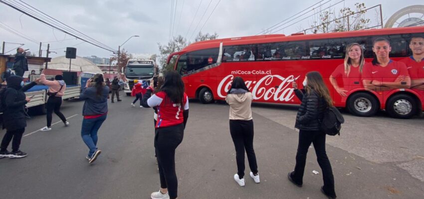 a la izquierda la cantante Catana, a la derecha el bus de la Selección Chile y también hinchas